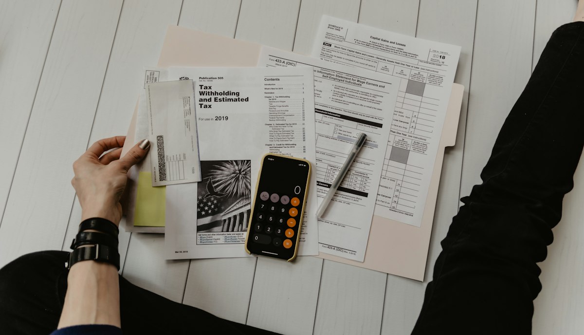 Hands reviewing printed account statements and a calculator during a retirement income analysis.
